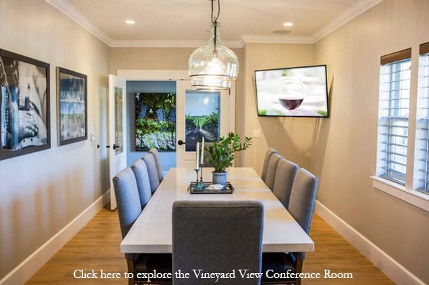 A conference room with a long table and chairs and a television on the wall.