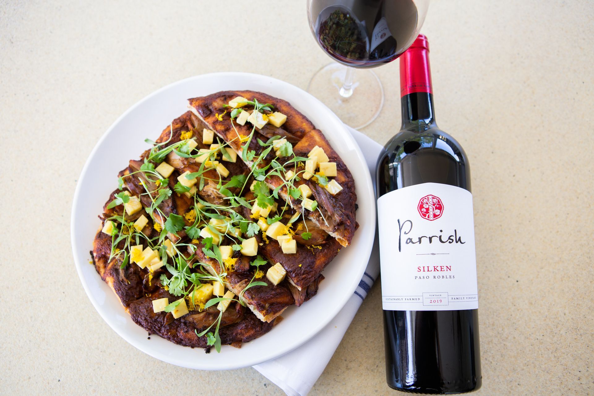 A bottle of parrish wine next to a plate of food.