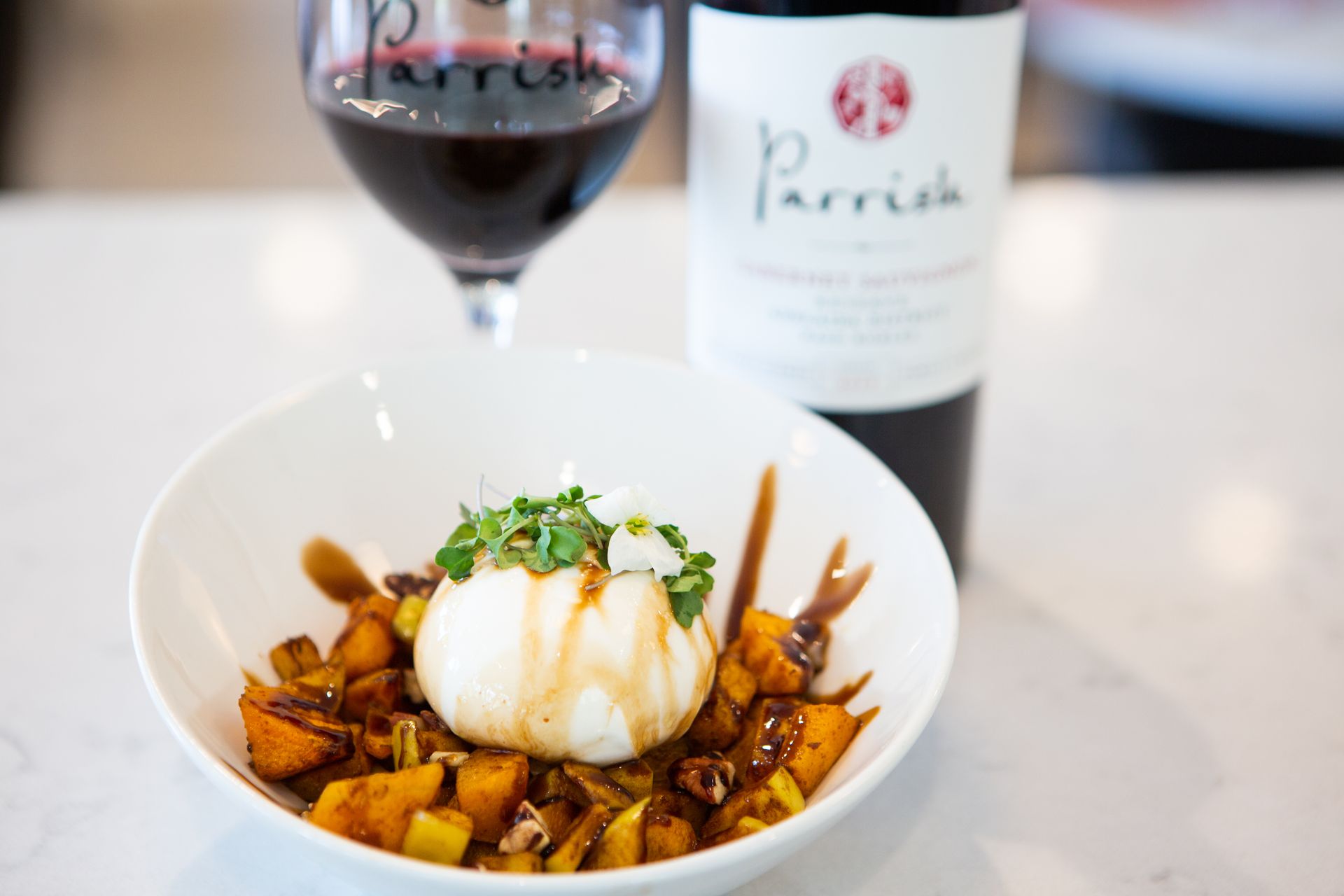 A bowl of food next to a bottle of parrish wine