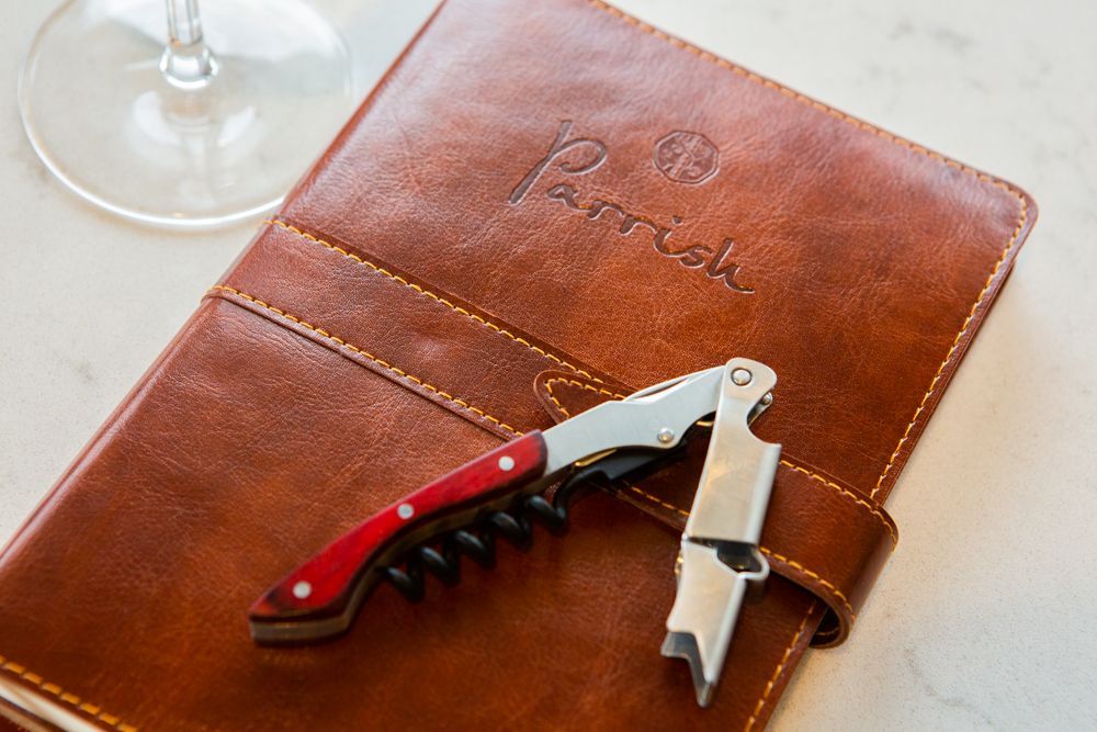 A corkscrew is sitting on top of a brown leather menu.