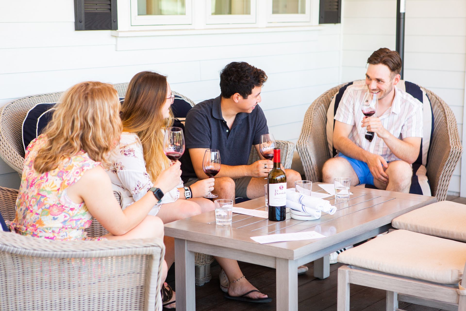 A group of people is sitting around a table tasting wine and smiling.