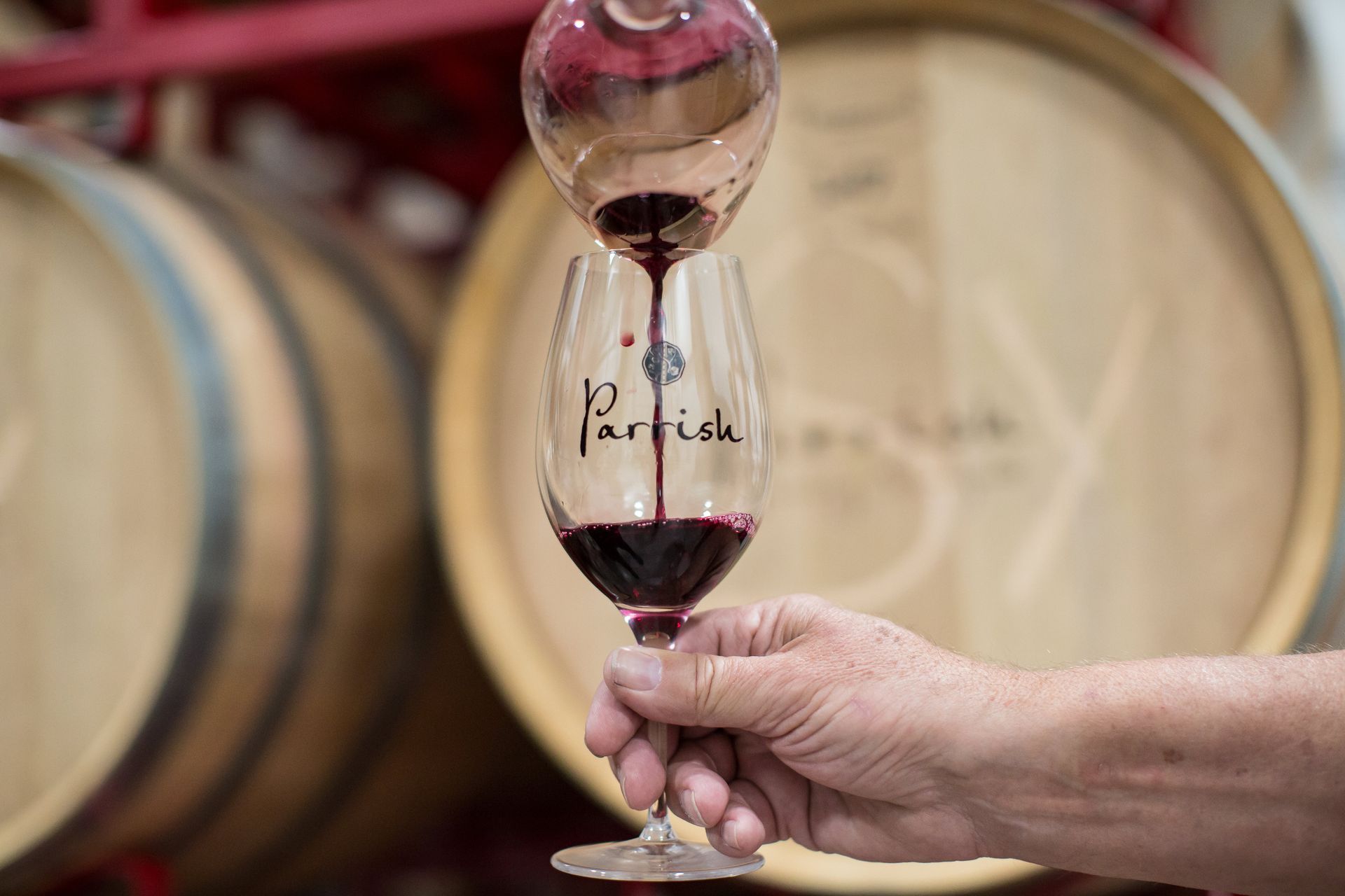 Glass of Cabernet Sauvignon in front of wine barrells.