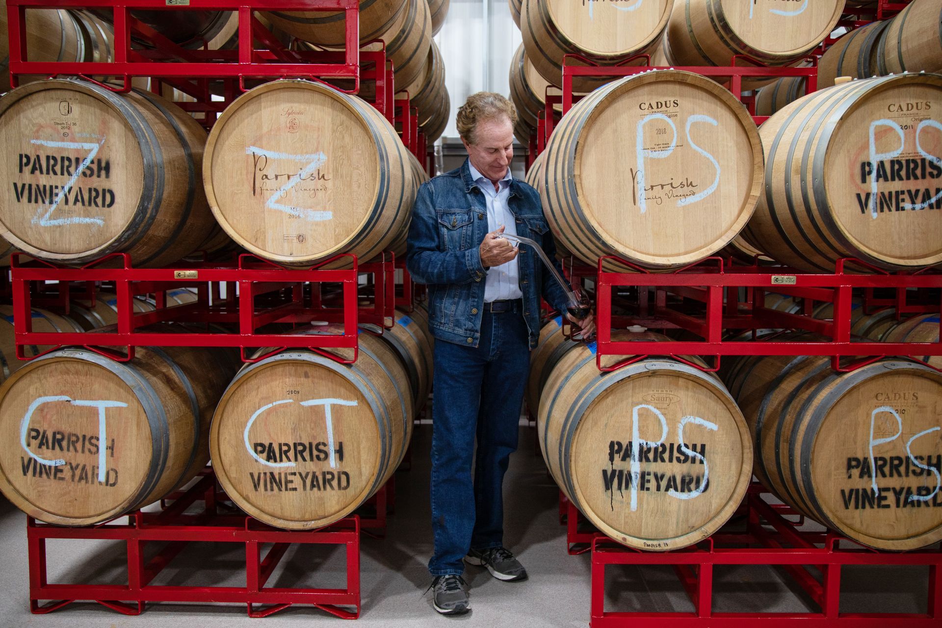 David Parrish standing between barrels with wine.
