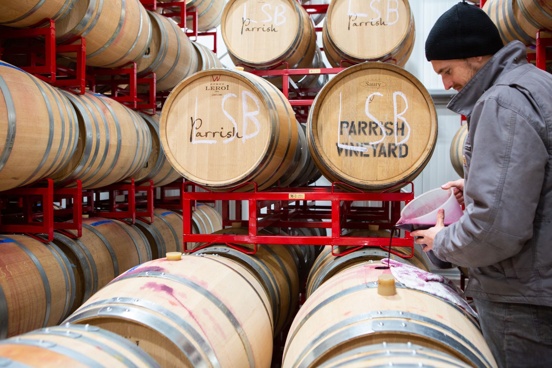 Multiple wine barrels with one being poured into.