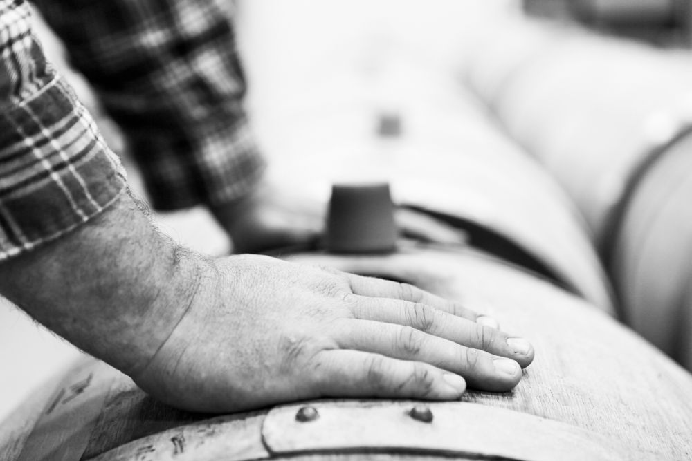A hand on a wine barrel.