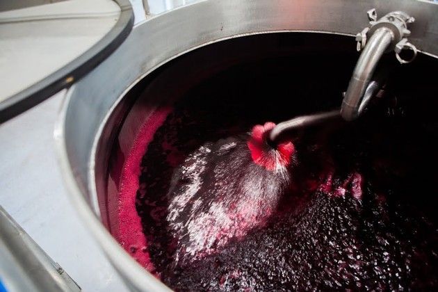 A large stainless steel container filled with red wine.
