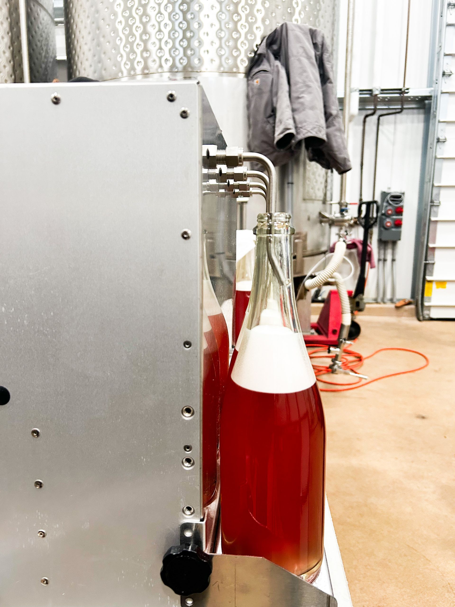 A wine bottle in the production room being filled with Parrish Family Vineyard's 2025 Grenache Pét-Nat.