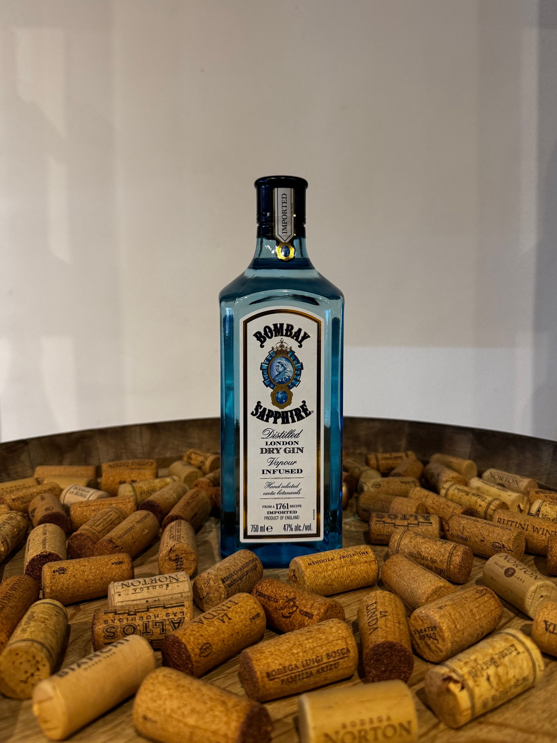 Botella de ginebra Blue Bombay Sapphire rodeada de corchos sobre una bandeja de metal.