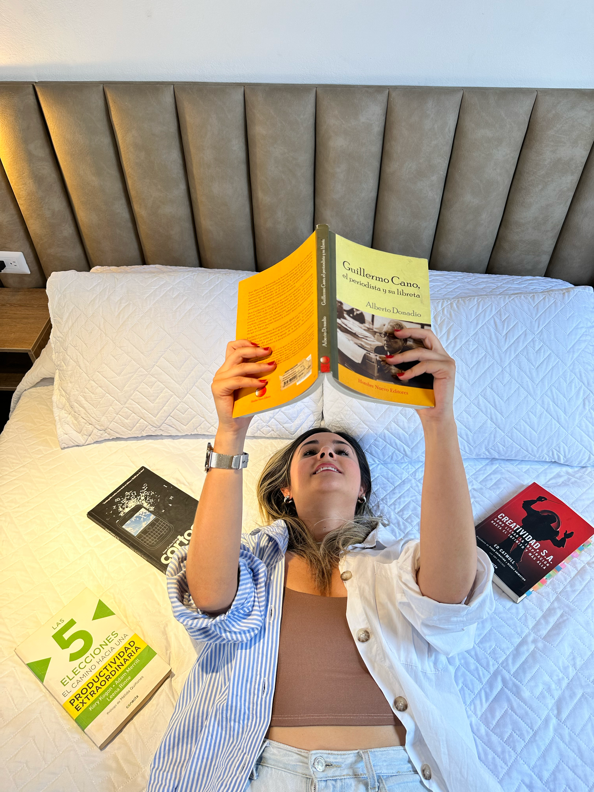 A woman is laying on a bed reading a book.