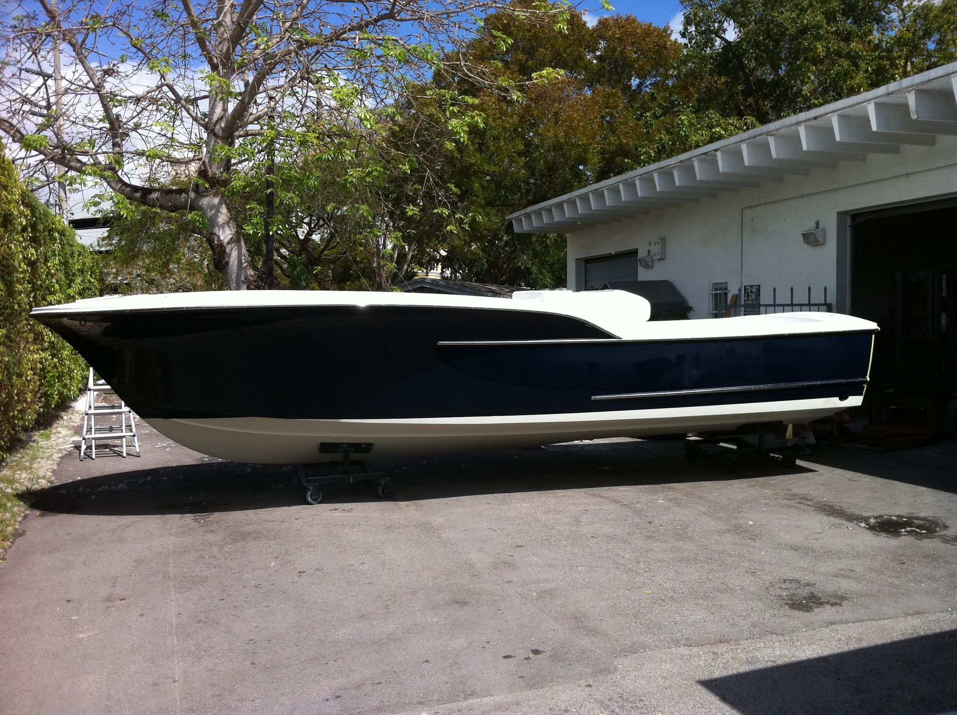 A row of boats are covered in white tarps and sitting on trailers.