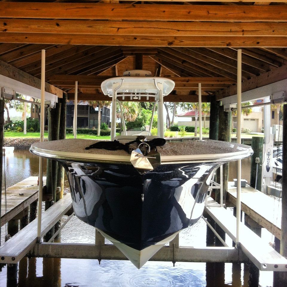 A row of boats are covered in white tarps and sitting on trailers.