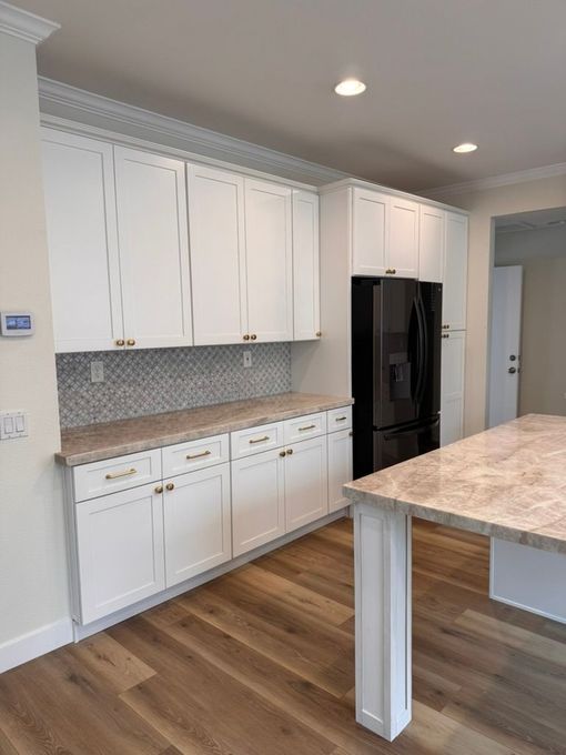 White kitchen remodel with waterfall island and wood flooring in San Diego