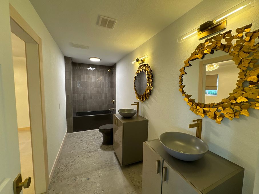 Powder room remodel with round gold mirror and dark vanity in Rancho Santa Fe