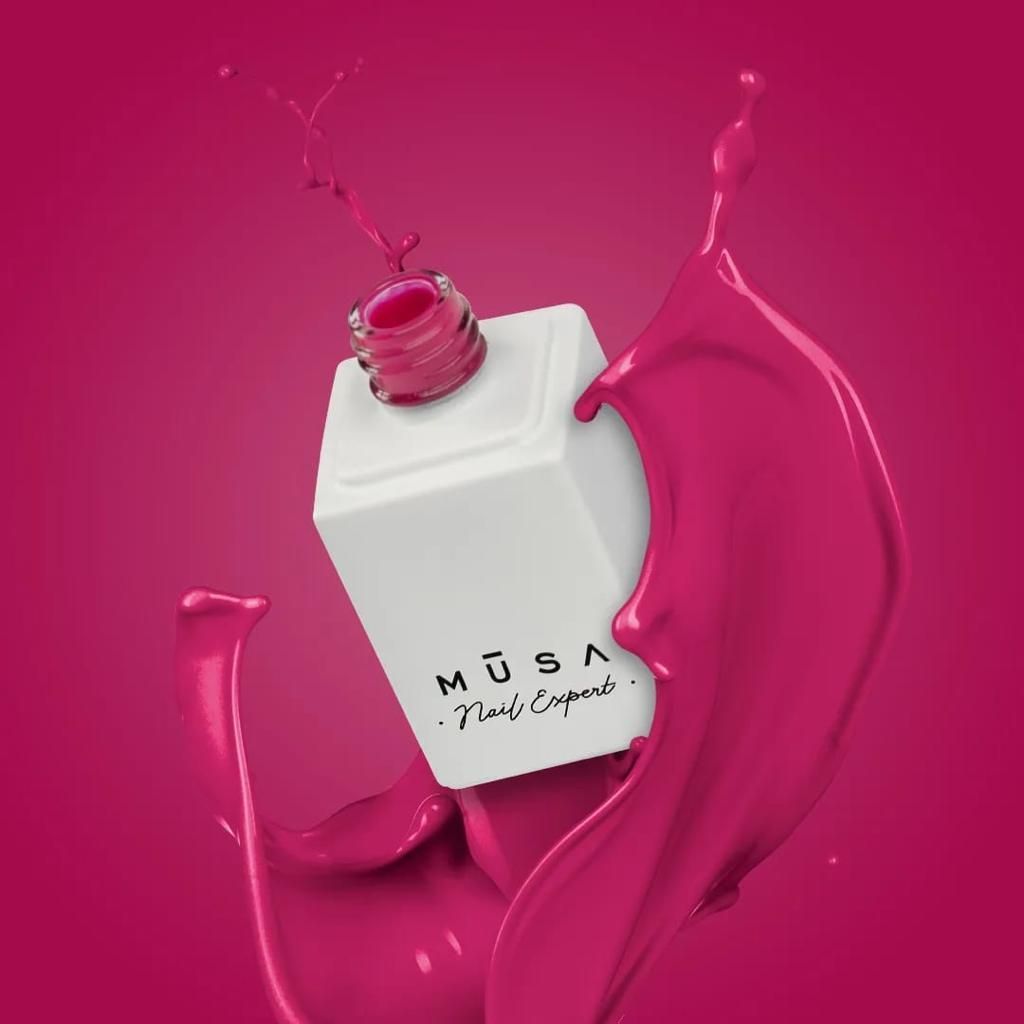 Una boccetta di smalto bianco con smalto rosa che fuoriesce su uno sfondo rosa.