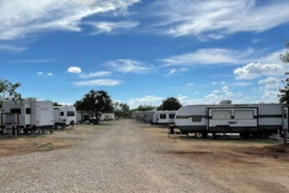 RV park with rows of parked recreational vehicles under a blue sky with scattered clouds.