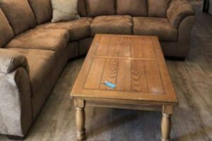 Brown sectional sofa and wooden coffee table in a room with wood-look flooring.
