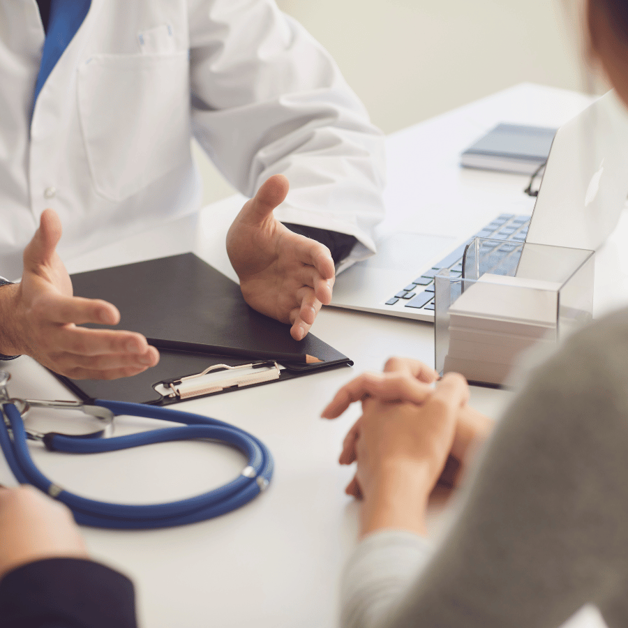 Doctor speaking with patient at a desk with stethoscope and medical paperwork