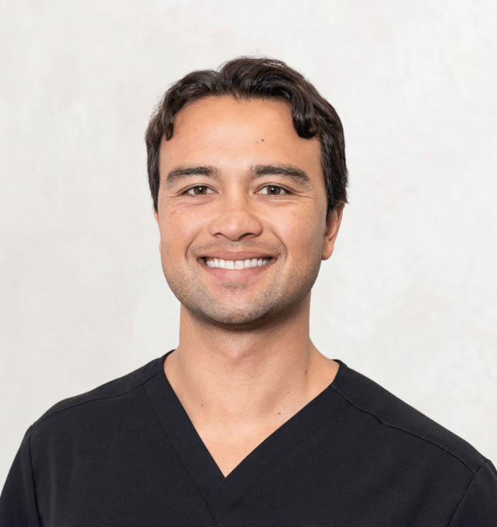 Smiling person in black scrub top with ECORE logo against a plain light background