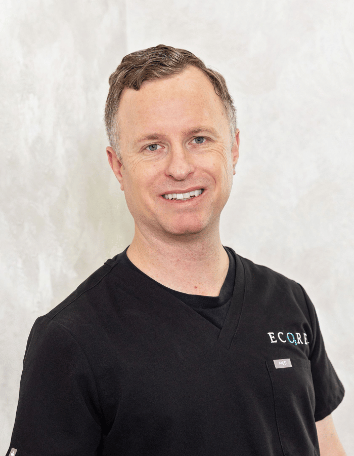 Smiling person in a black shirt with ECCO logo, standing against a light background