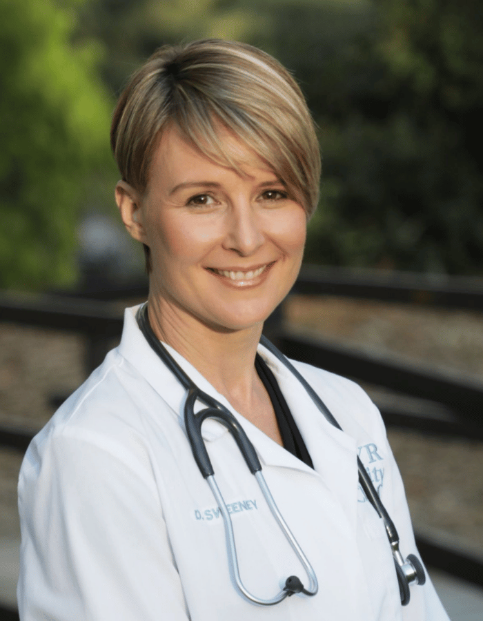Smiling medical professional in a white coat with a stethoscope outdoors
