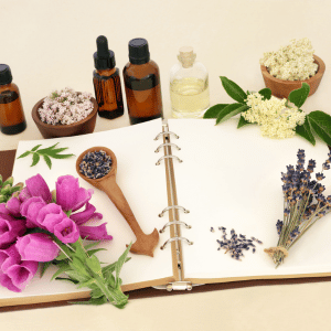 Open journal surrounded by lavender, herbs, and amber essential oil bottles on a table