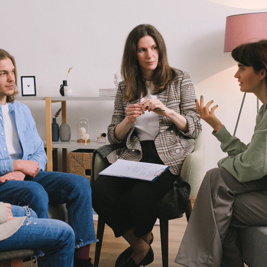 Small group in a counseling session, seated in a circle and talking in a bright room.
