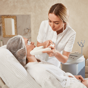 Aesthetician applying facial treatment to reclining client in a spa room