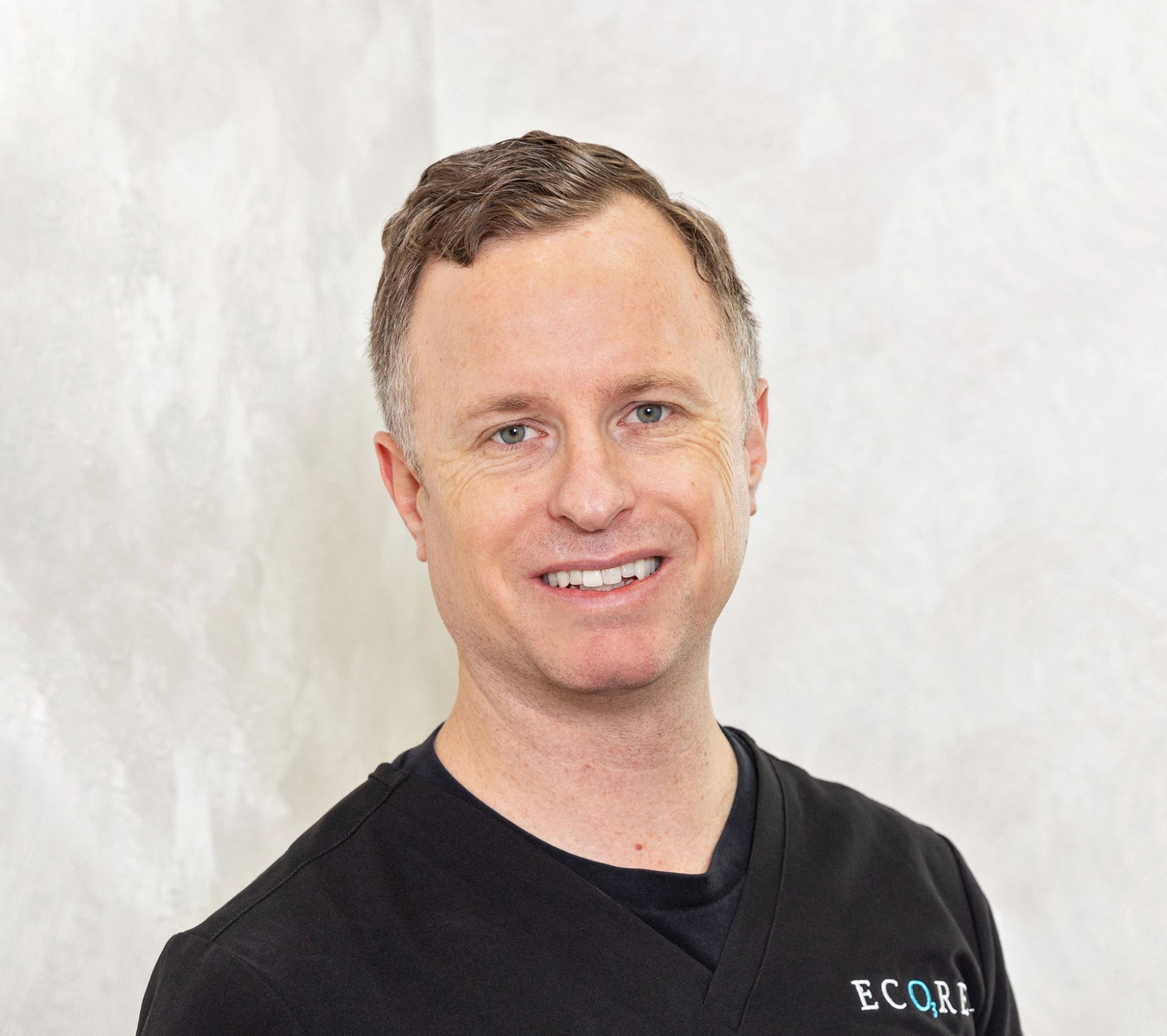 Smiling man in a black shirt against a light textured background