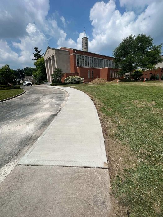 Curved sidewalk beside a red brick building under a partly cloudy sky.