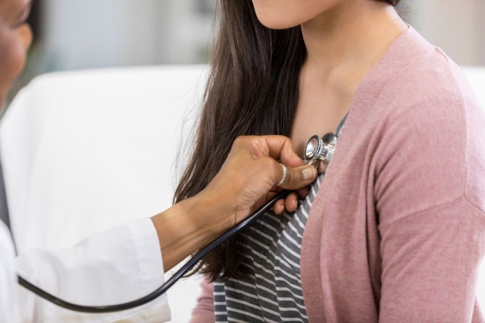 medico mentre ascolta il battito di una paziente
