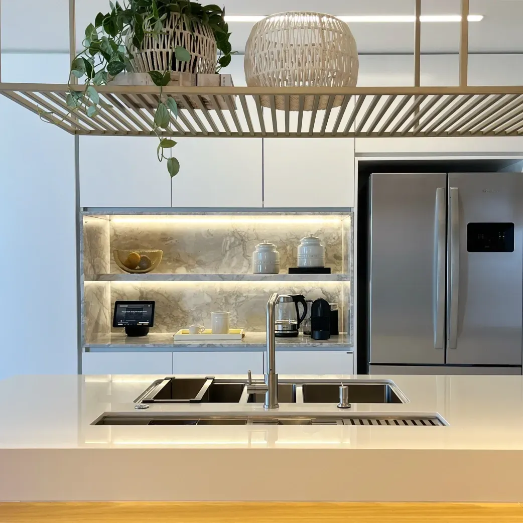 Cozinha moderna com armários brancos, eletrodomésticos de aço inoxidável, backsplash de mármore e detalhes em madeira.