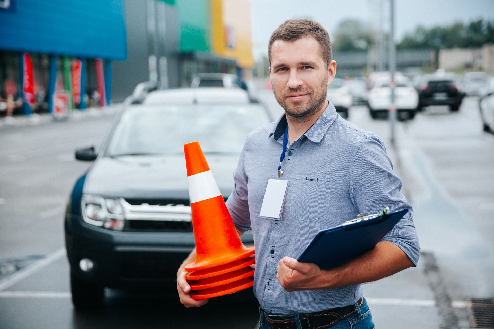 A Man is Holding a Stack of Traffic Cones and a Clipboard in Front of a Car