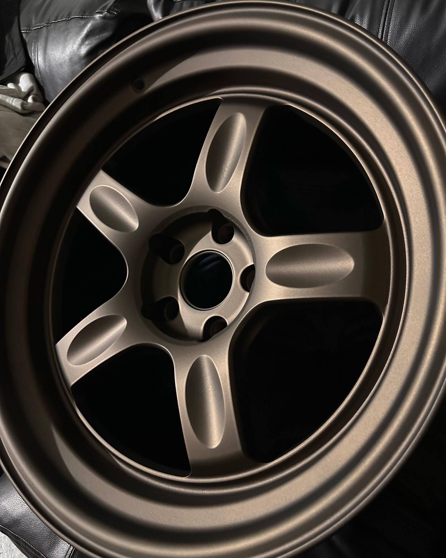 Bronze five-spoke alloy car wheel rim on a black background