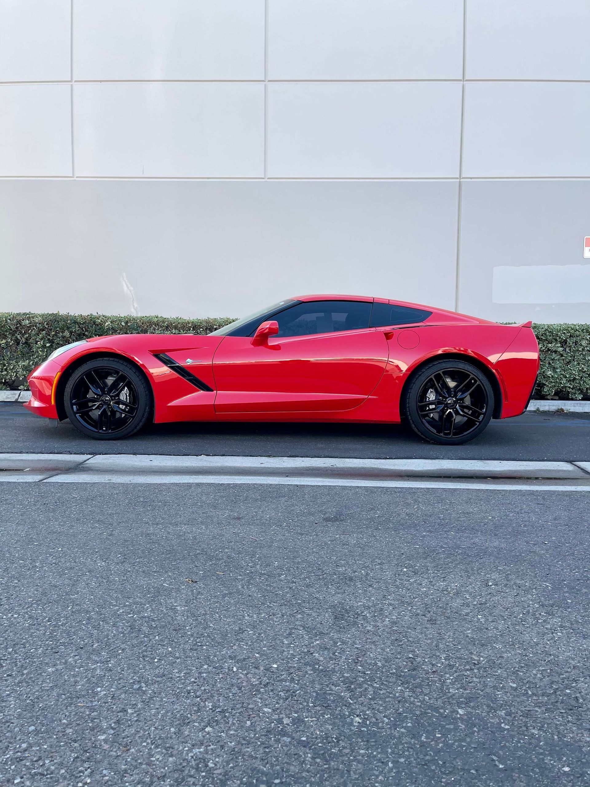 Red sports car parked in profile against a light gray wall.