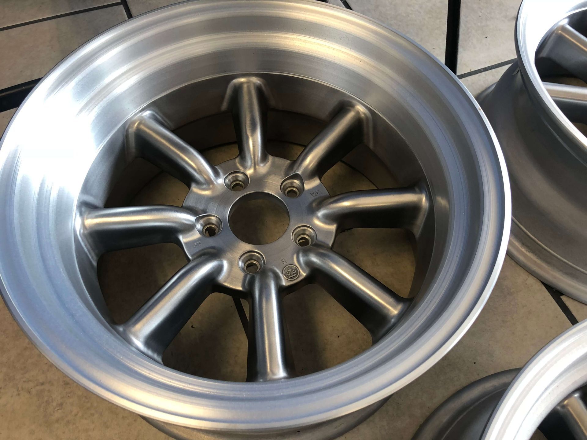 Close-up of a silver alloy wheel rim with multiple spokes on a workbench