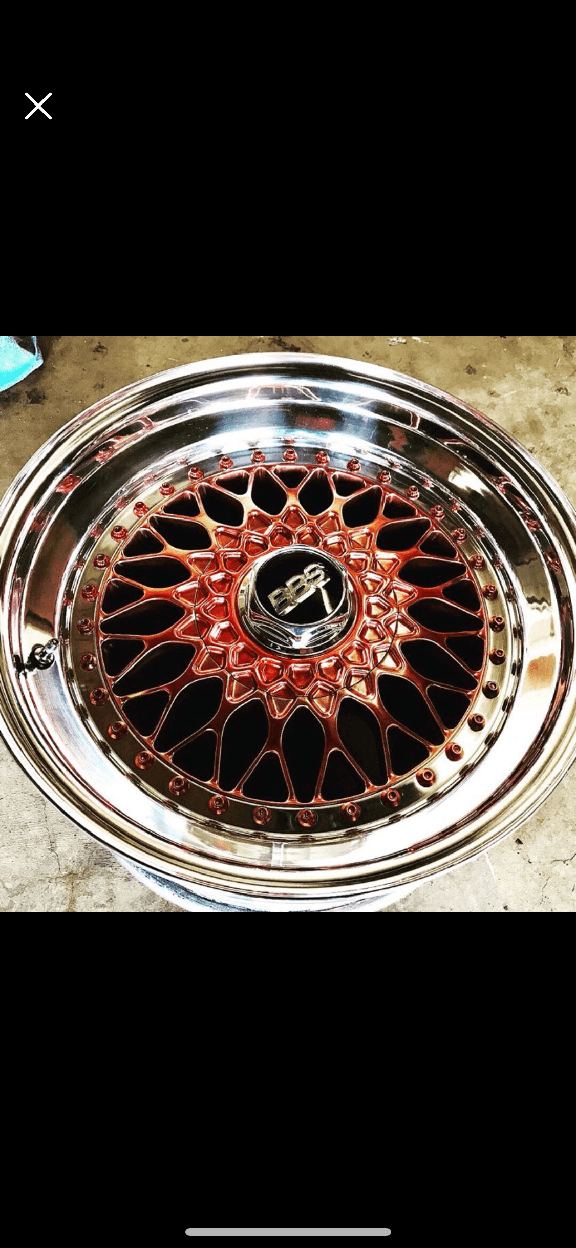Close-up of a metal wheel rim with a red and black spiderweb pattern in the center.