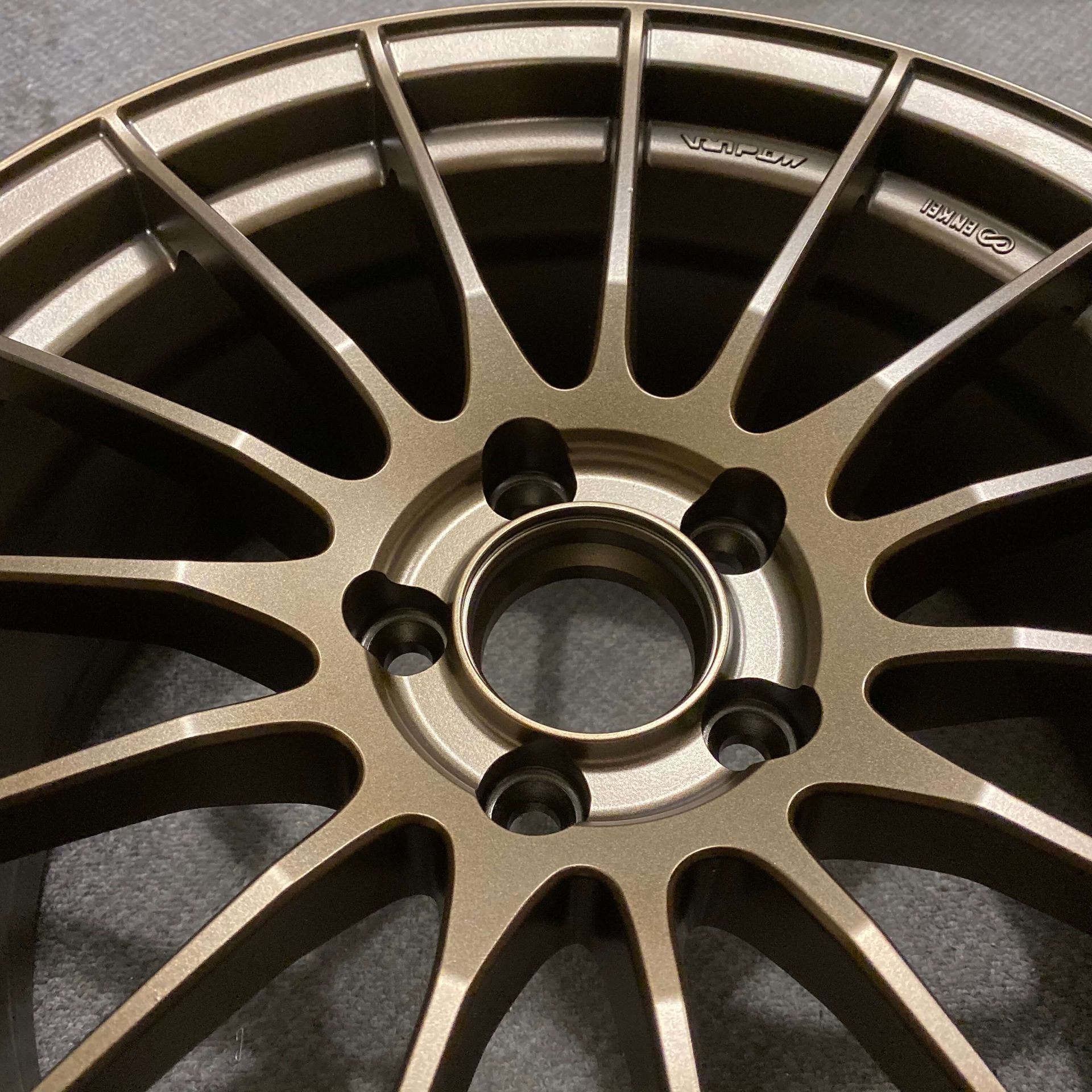 Close-up of a bronze alloy car wheel rim with multiple spokes and five lug holes