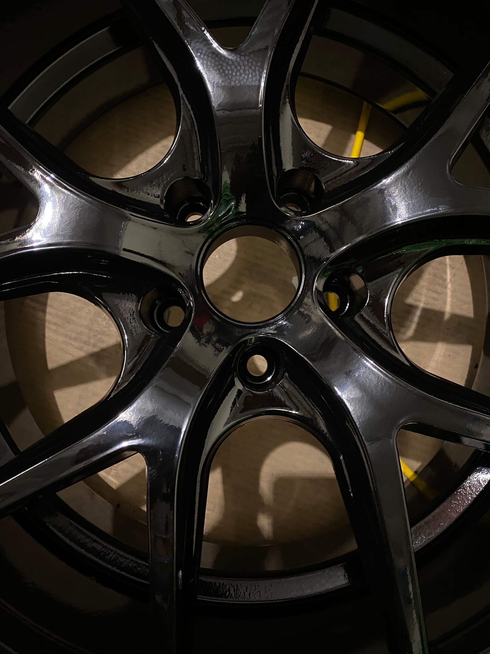 Close-up of a glossy black car wheel rim with five spokes and a central hub