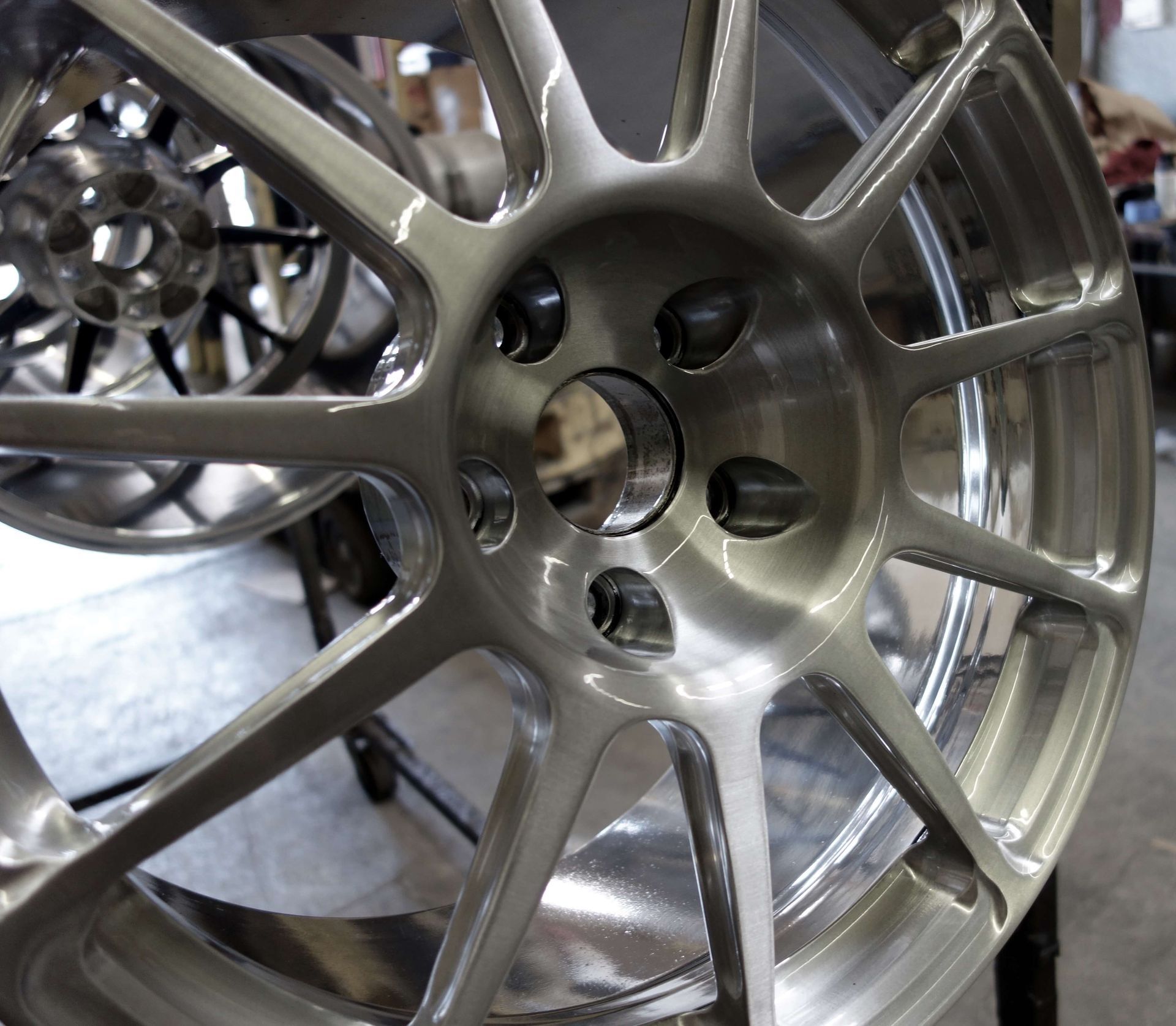 Silver alloy car wheel rim with multiple spokes, shown close-up on a display stand.