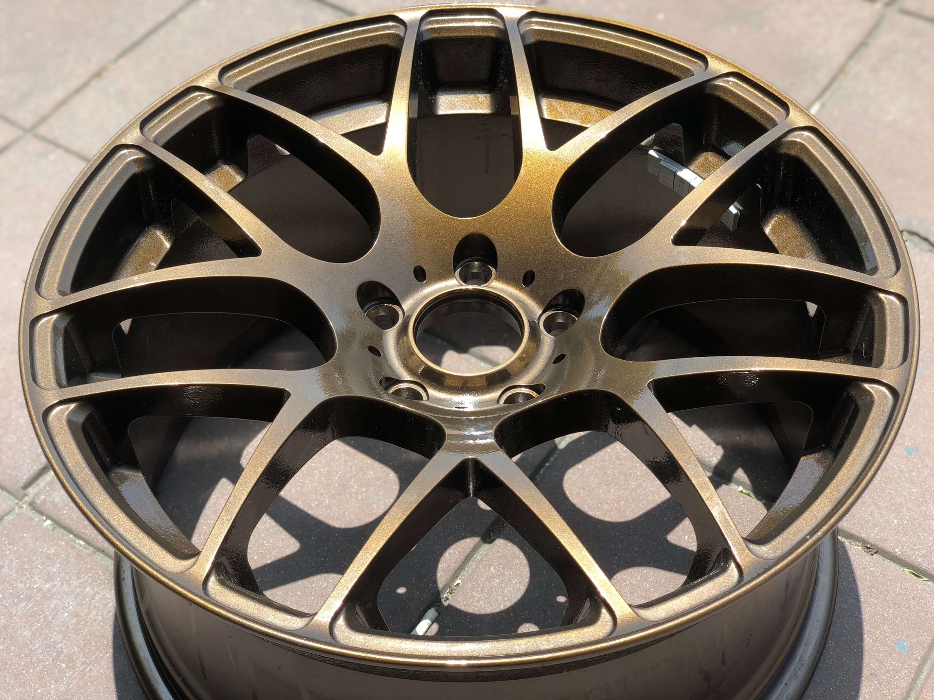 Black multi-spoke alloy car wheel rim on a light surface