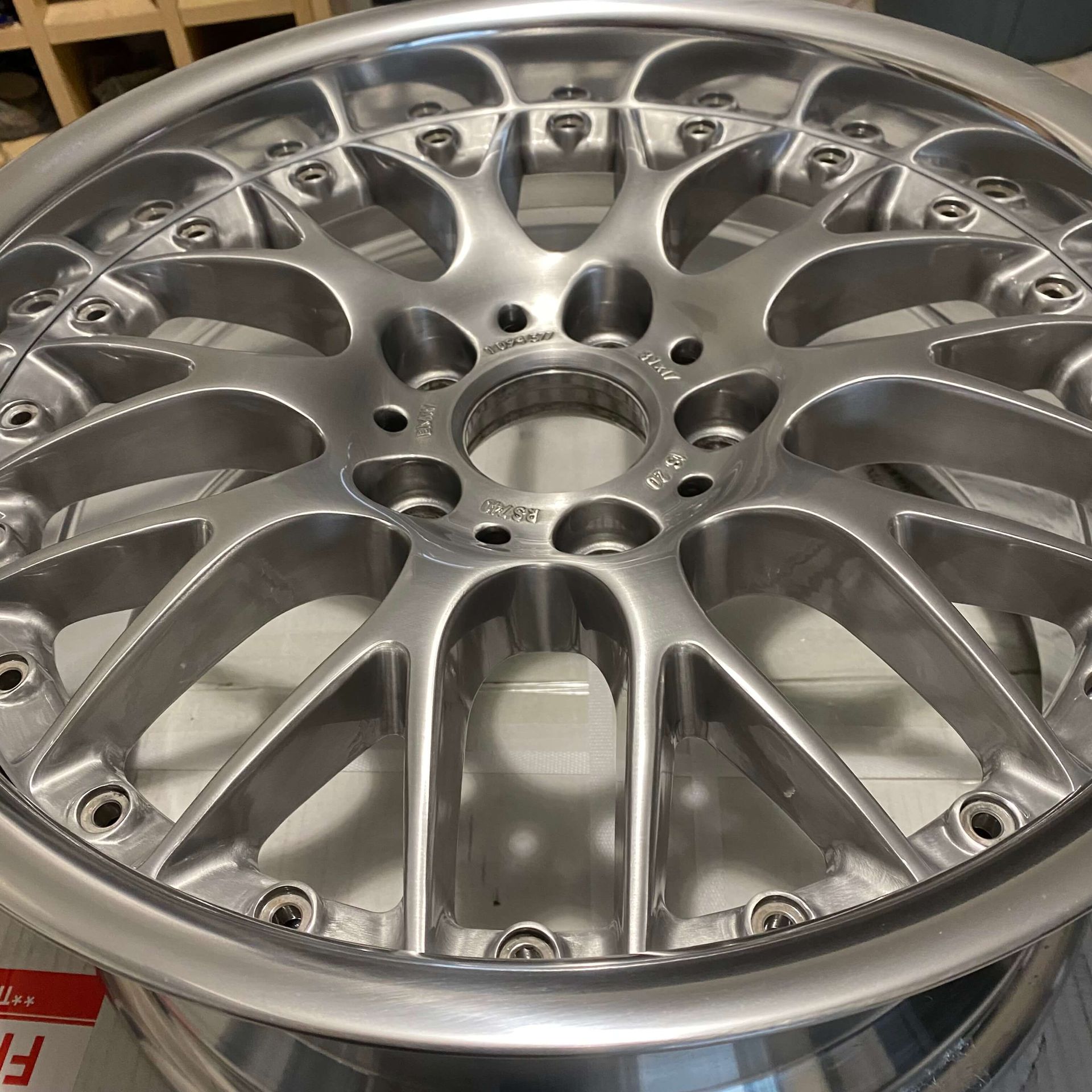 Silver multi-spoke alloy wheel rim close-up on a table with visible lug holes and polished finish