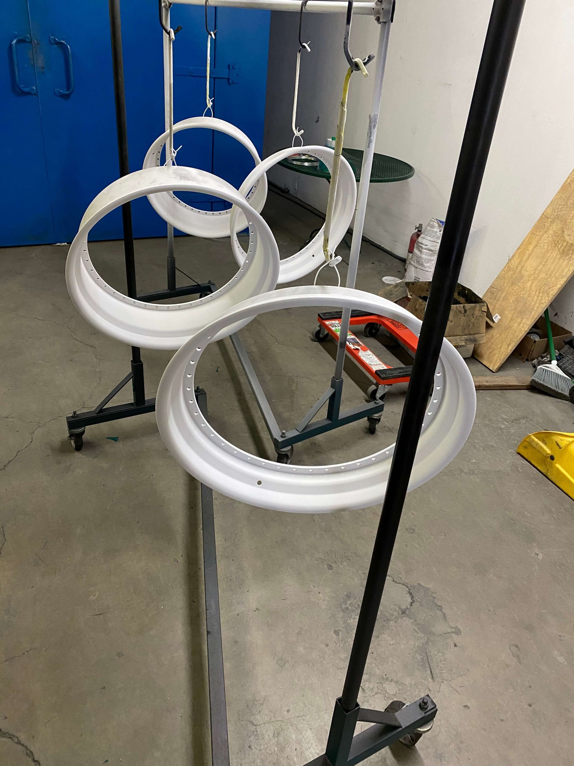Three white circular rings hanging on a metal frame in a workshop