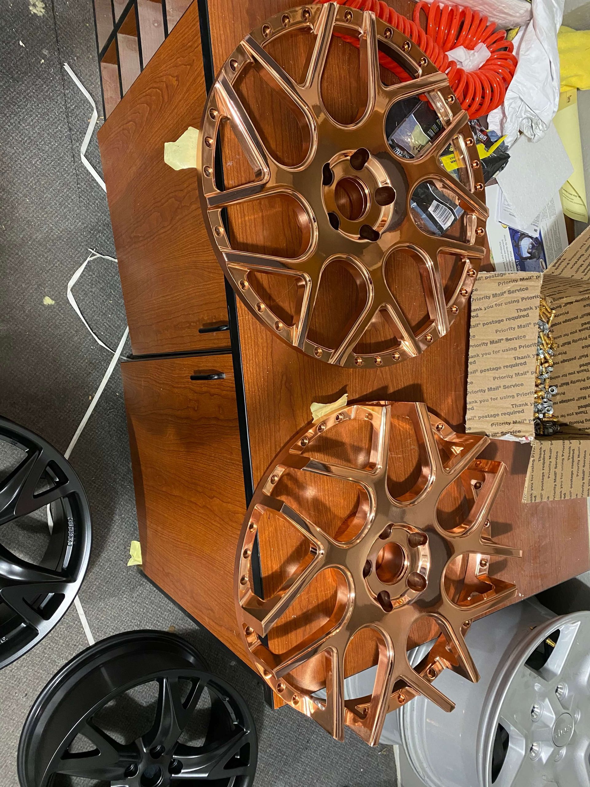 Copper and black decorative wheel sculptures displayed outdoors beside parked cars.