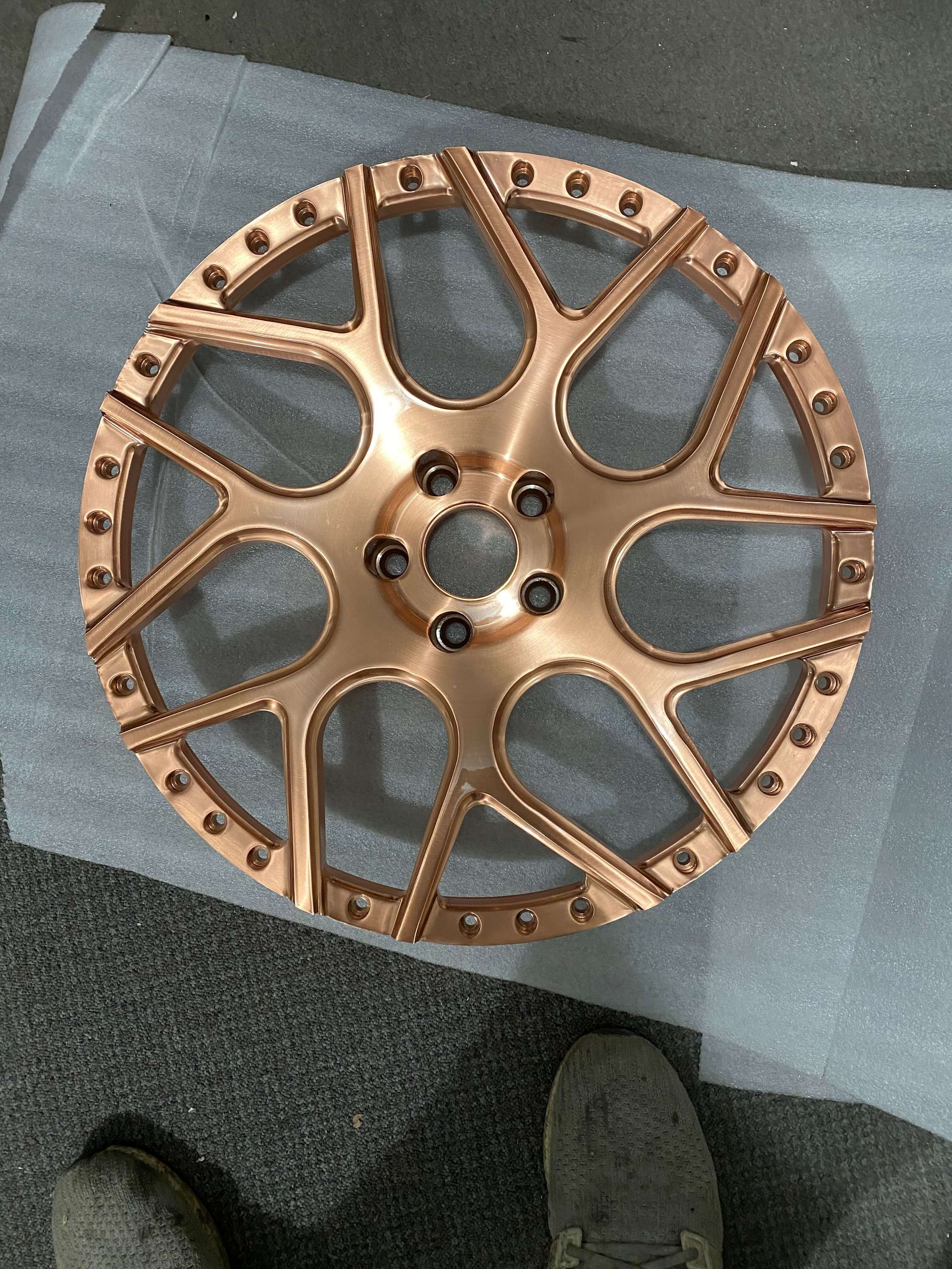 Copper-colored spoked wheel or gear lying on a dark surface, seen through clear plastic wrap