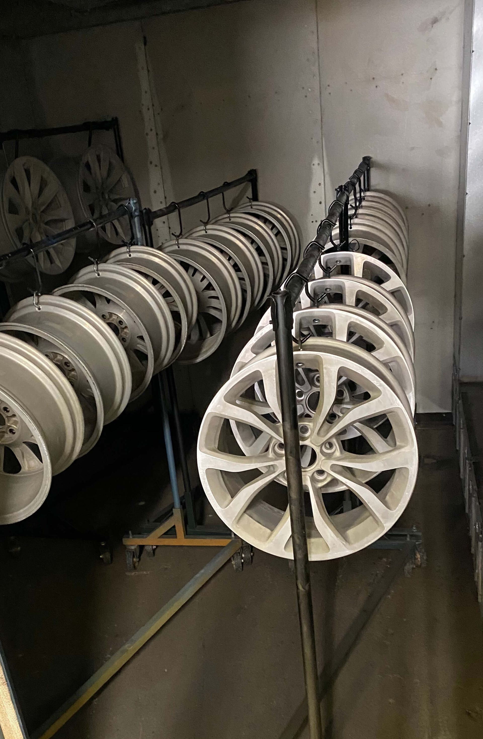 Rows of white wheels stored on metal racks in a dim industrial room