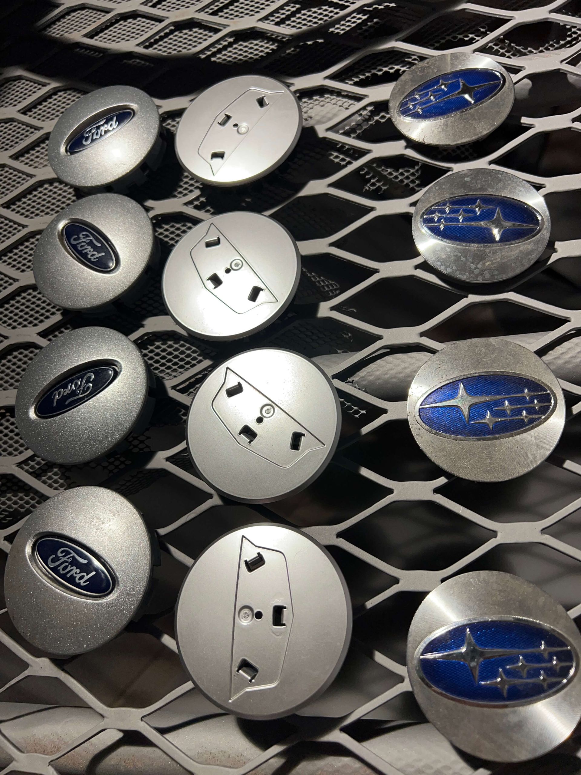 Close-up of silver and blue Subaru car emblems arranged on a metal mesh surface