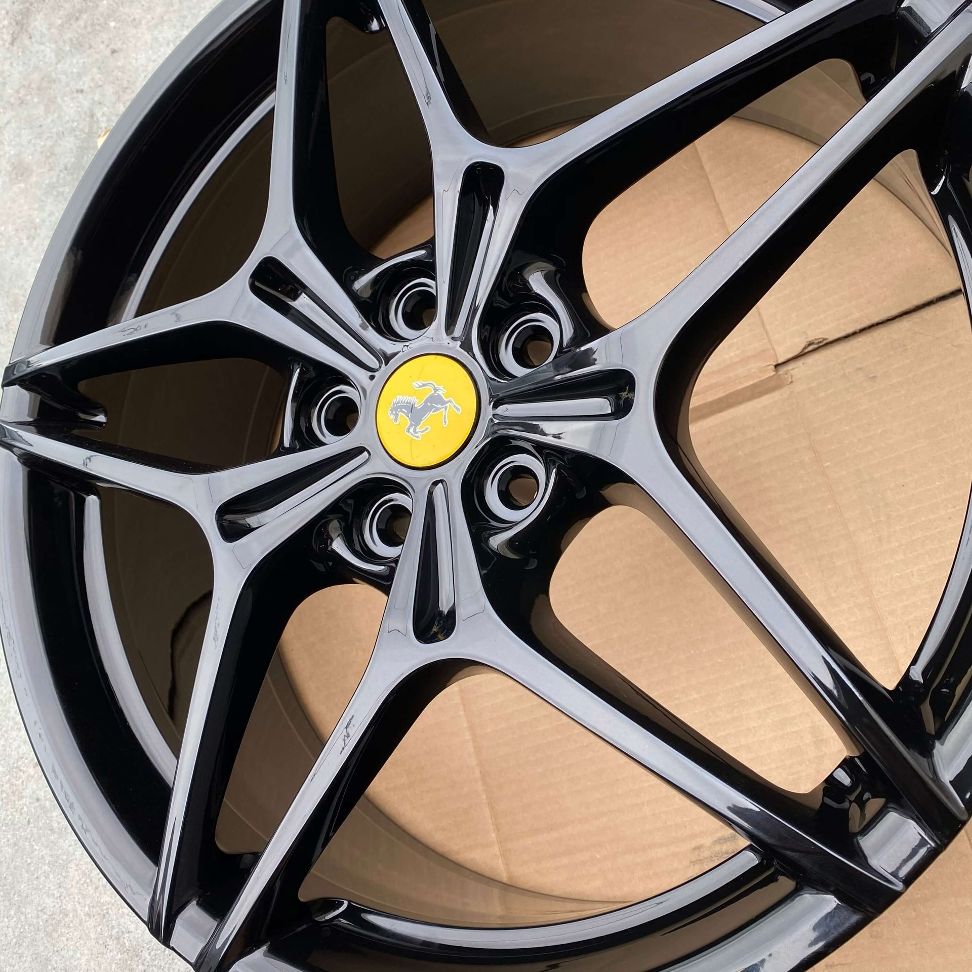 Black alloy car wheel rim with a yellow center emblem on cardboard packaging