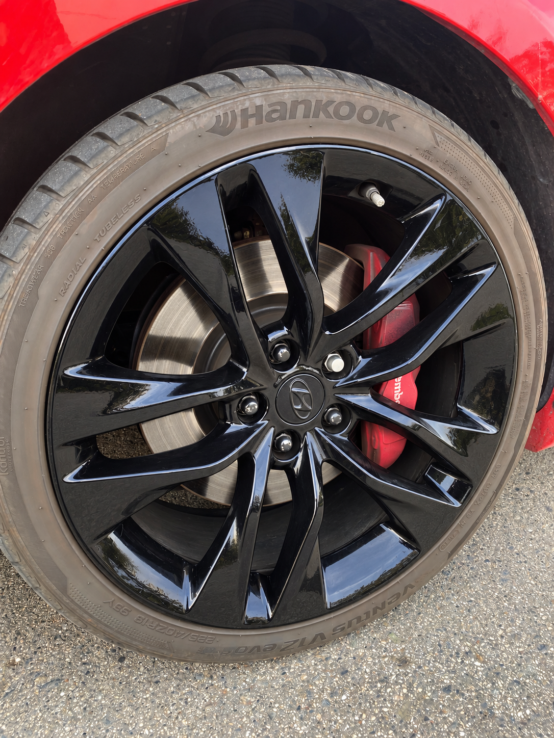 Close-up of a black car wheel with a Hankook tire and red brake caliper.