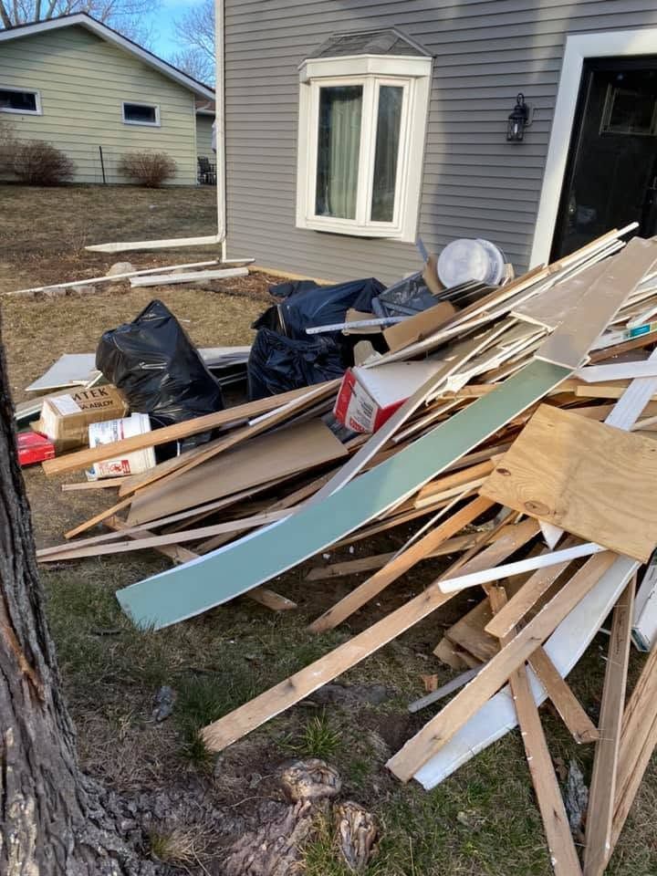 Pile of broken wood and debris stacked beside a house after cleanup or demolition