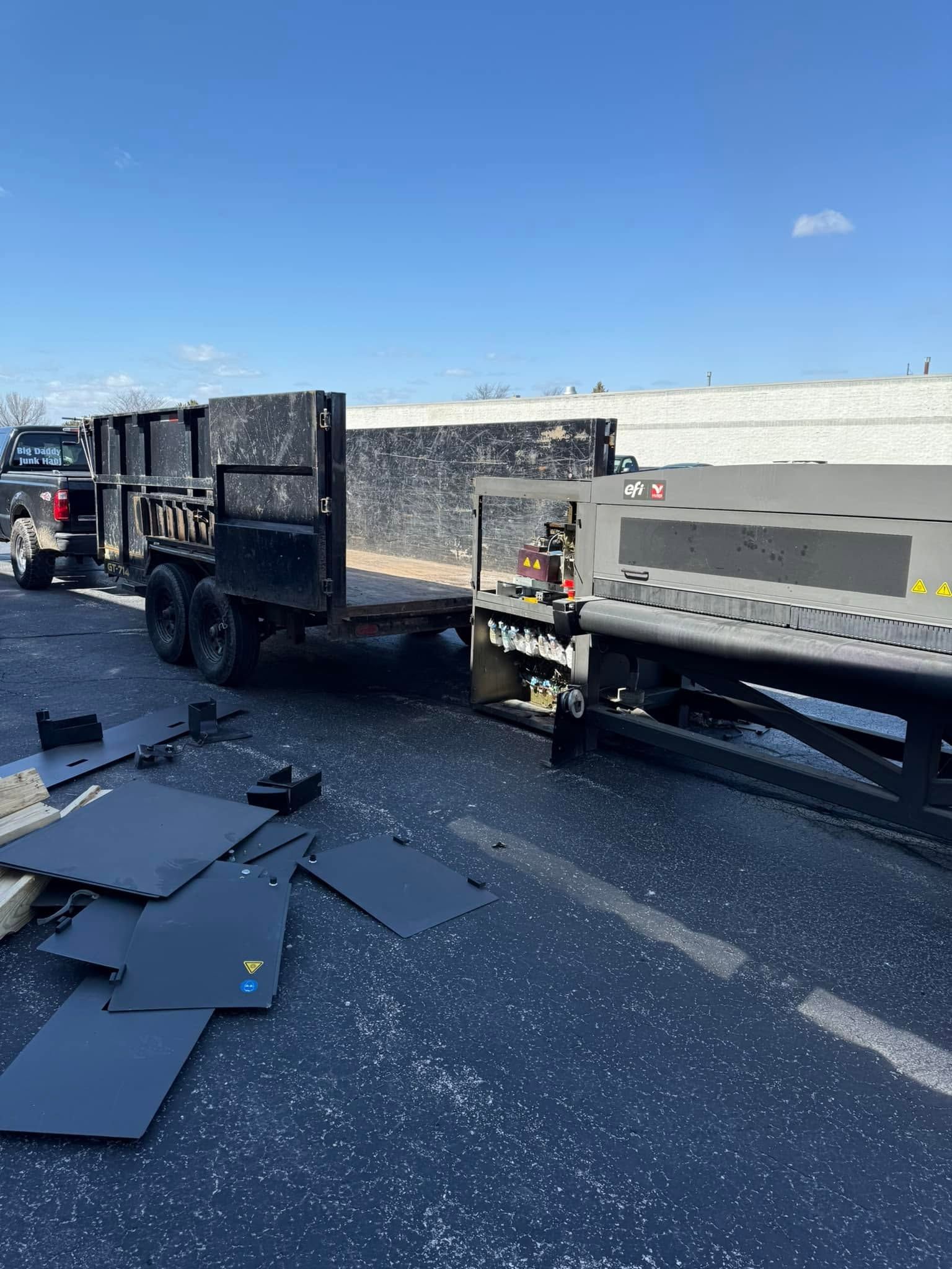 Overturned flatbed trailer on highway shoulder with debris scattered across the road under a clear blue sky